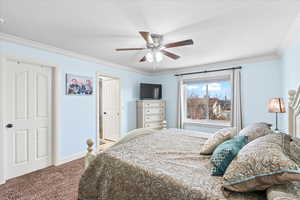 Bedroom with ceiling fan, ornamental molding, and carpet flooring