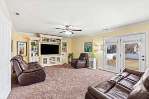 Carpeted living room with ceiling fan and ornamental molding