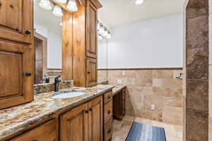 Bathroom featuring tile walls, vanity, and a textured ceiling