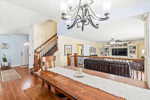 Dining area with ceiling fan with notable chandelier, crown molding, and hardwood / wood-style flooring