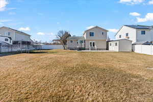 Back of house with a lawn, a trampoline, and a storage unit