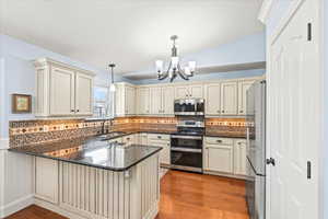 Kitchen with stainless steel appliances, sink, kitchen peninsula, and decorative light fixtures