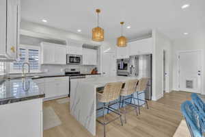 Kitchen featuring appliances with stainless steel finishes, sink, white cabinetry, and a center island