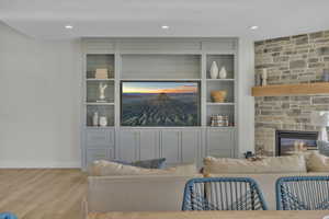 Living room with light hardwood / wood-style floors, built in shelves, and a fireplace