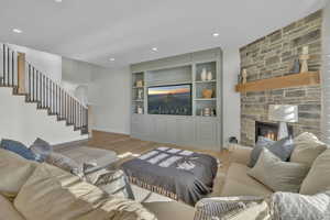 Living room with built in features, light wood-type flooring, and a fireplace