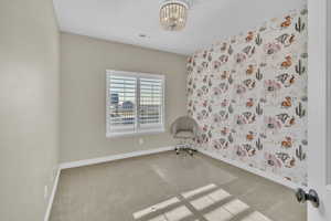 Unfurnished room featuring an inviting chandelier and carpet flooring