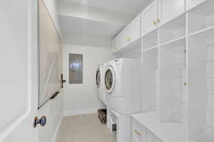 Washroom with cabinets, light tile patterned floors, washer and clothes dryer, and electric panel