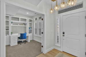 Entrance foyer featuring built in desk, a wealth of natural light, and light hardwood / wood-style flooring