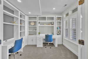 Home office featuring light colored carpet and built in desk