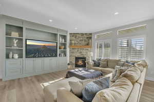 Living room featuring light hardwood / wood-style floors, a fireplace, and built in shelves