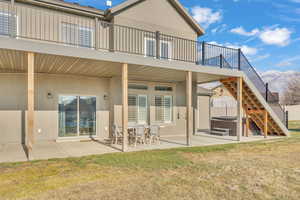 Rear view of house with a lawn, a hot tub, and a patio