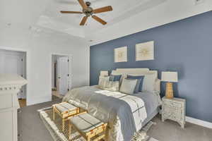 Carpeted bedroom with ceiling fan, crown molding, and a tray ceiling