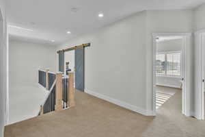 Hall with light carpet and a barn door