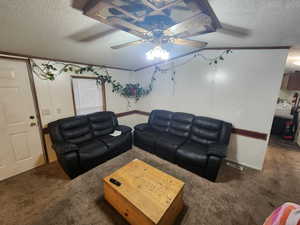 Living room with ceiling fan, crown molding, a textured ceiling, and carpet flooring