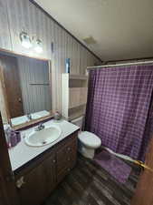 Bathroom with a textured ceiling, wood-type flooring, vanity, toilet, and crown molding