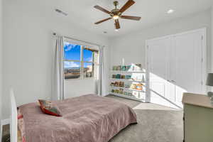 Carpeted bedroom with ceiling fan and a closet