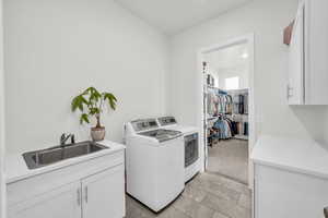 Laundry area featuring washer and dryer, cabinets, light colored carpet, and sink