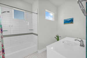 Bathroom with shower / bath combo, tile patterned flooring, and sink