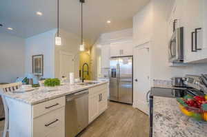 Kitchen featuring a center island with sink, a breakfast bar area, stainless steel appliances, white cabinets, and sink