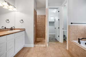 Full bathroom featuring tile patterned floors, vanity, toilet, and shower with separate bathtub