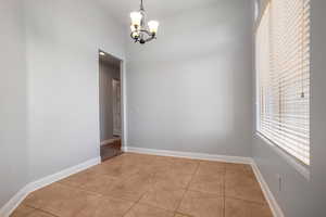 Tiled spare room featuring an inviting chandelier