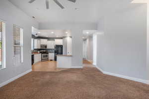 Kitchen with black appliances, white cabinets, a wealth of natural light, and light colored carpet