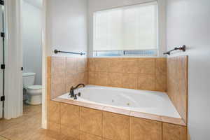 Bathroom featuring toilet, tile patterned floors, and tiled tub