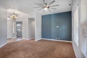 Carpeted spare room with ceiling fan with notable chandelier