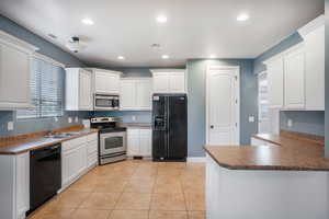 Kitchen featuring sink, white cabinetry, and black appliances