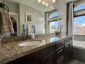 Bathroom with vanity, a wealth of natural light, and tiled tub