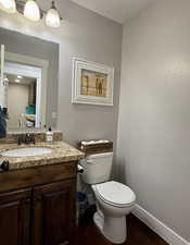 Bathroom featuring hardwood / wood-style floors, toilet, and vanity- Half bath