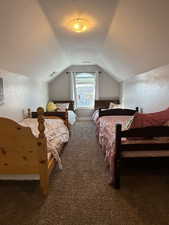 Bedroom with vaulted ceiling and dark colored carpet