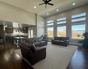 Living room with ceiling fan, a high ceiling, and dark hardwood / wood-style flooring