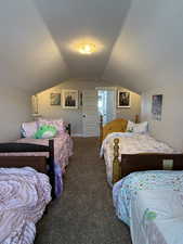 Bedroom with lofted ceiling and dark colored carpet