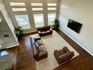 Living room featuring dark wood-type flooring and a high ceiling