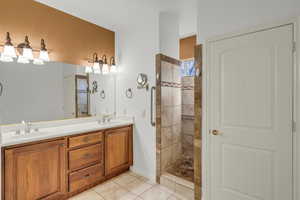 Primary Bathroom with vanity, tile patterned flooring, and a tile shower.