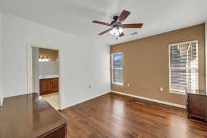 Primary bedroom with ceiling fan and dark wood-type flooring