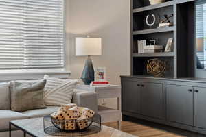 Sitting room with wood-type flooring and built in shelves