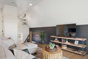 Living room with hardwood / wood-style flooring, high vaulted ceiling, wood walls, and a notable chandelier