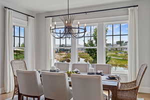 Dining space featuring plenty of natural light, wood-type flooring, a notable chandelier, and a water view