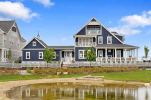 Back of house with a water view, a balcony, and a yard