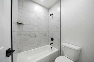 Bathroom with tiled shower / bath combo and toilet