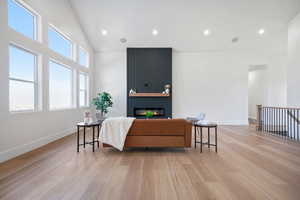 Living room with lofted ceiling, a fireplace, and light hardwood / wood-style floors