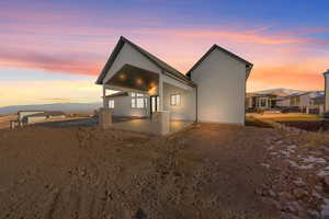 Back house at dusk featuring a mountain view and a patio