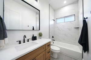 Full bathroom featuring toilet, tile patterned flooring, tiled shower / bath combo, and vanity