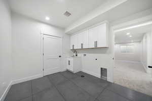 Laundry room featuring electric dryer hookup, sink, hookup for a washing machine, dark carpet, and cabinets