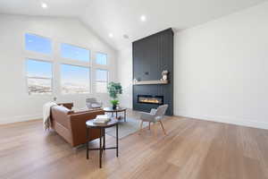 Living room with high vaulted ceiling, a fireplace, and light hardwood / wood-style floors