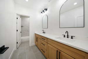 Bathroom with tiled shower / bath combo, vanity, and tile patterned flooring