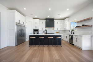 Kitchen featuring a center island, sink, light hardwood / wood-style flooring, stainless steel appliances, and white cabinets