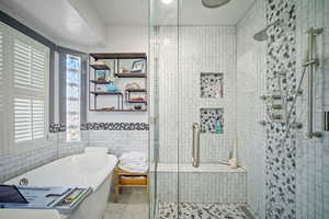 Bathroom featuring tile patterned flooring, tile walls, and shower with separate bathtub